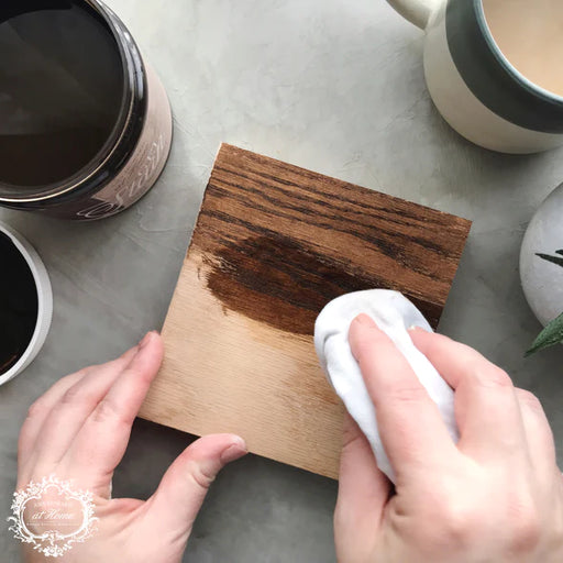 a person using a cloth to clean a wooden cutting board