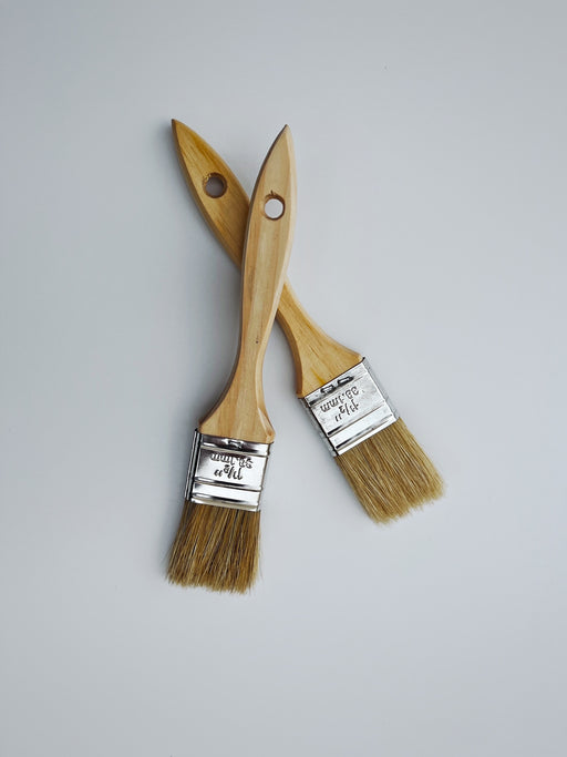 two paintbrushes sitting side by side on a white surface