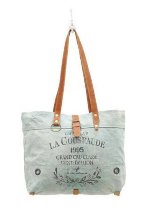 a blueish-gray tote bag with a brown leather handle on a white background
