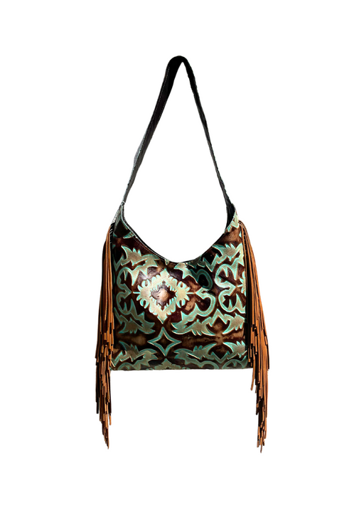 a hobo purse with a fringe hanging from a strap and a stamped leather design