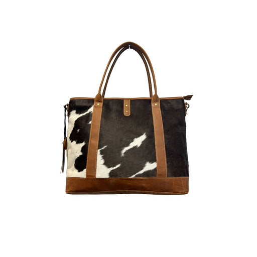 a black and white cow print purse with brown straps