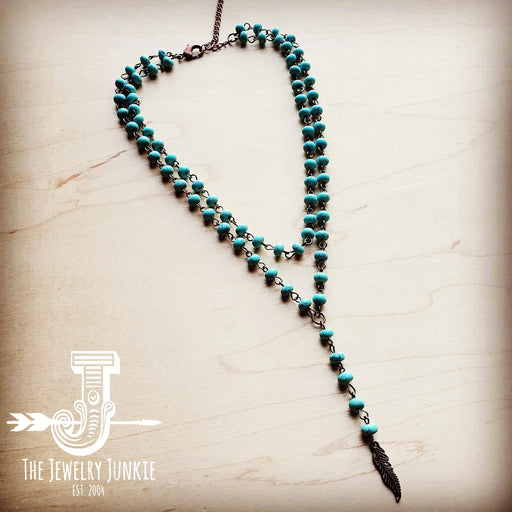 a turquoise beaded necklace with a feather charm