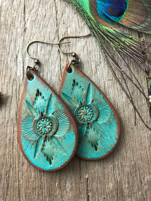 a pair of turquoise earrings with a flower design