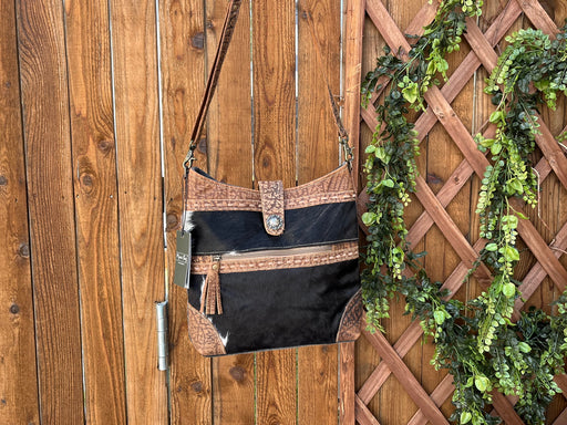 a purse hanging on a wooden fence next to a plant