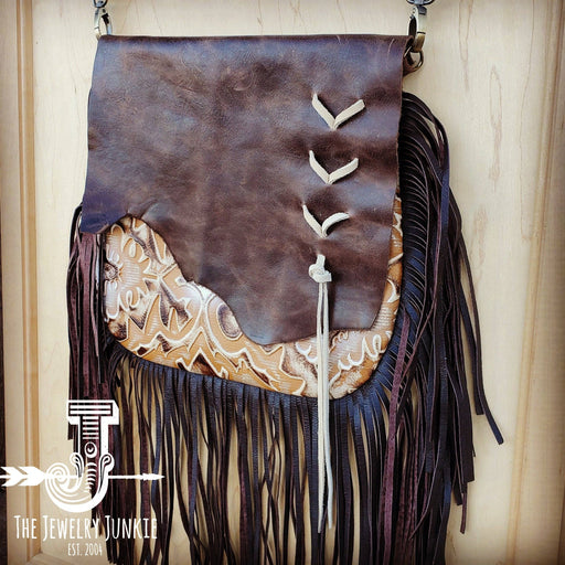 a brown leather purse with fringes hanging on a wall