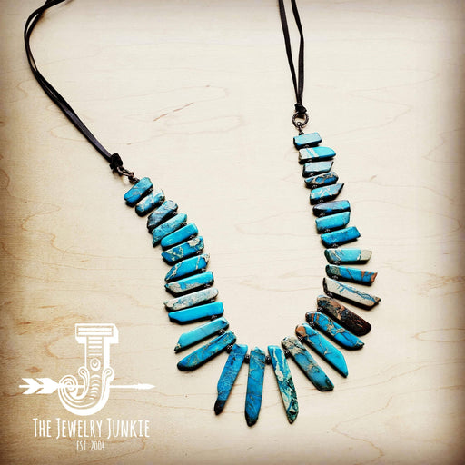 a necklace made of turquoise stones on a black cord