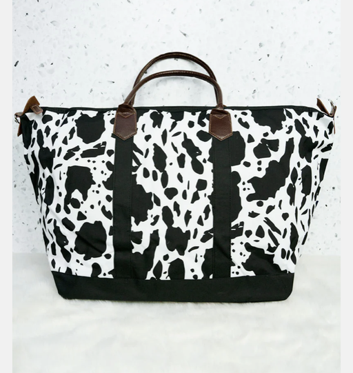a black and white animal print bag with brown handles