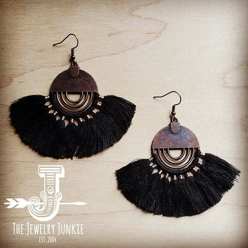 a pair of black tasseled earrings on a wooden surface