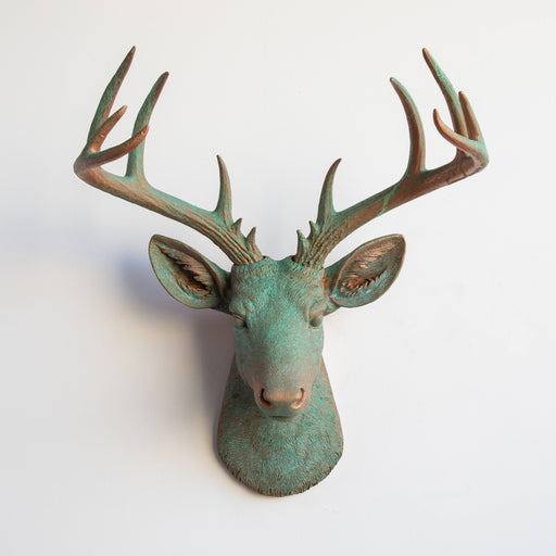 a copper and green patina deer head mounted on a wall