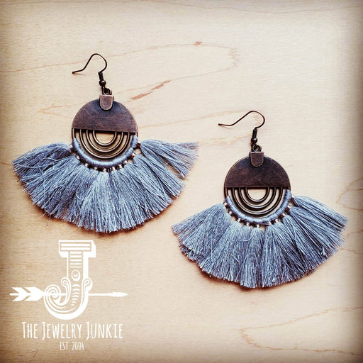 a pair of tasseled earrings on a wooden surface