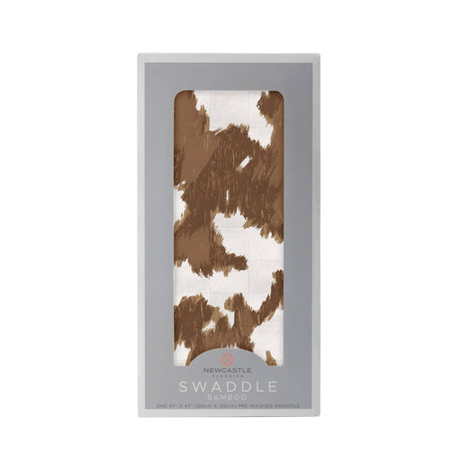 a brown and white cowprint swaddle blanket in a package