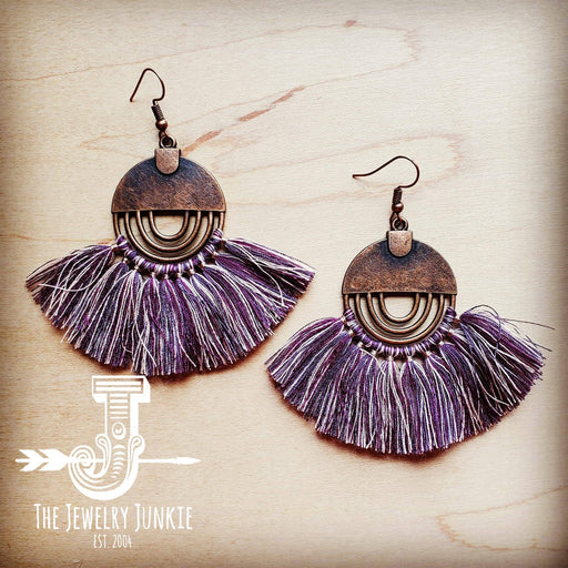 a pair of purple tasselled earrings on a wooden surface