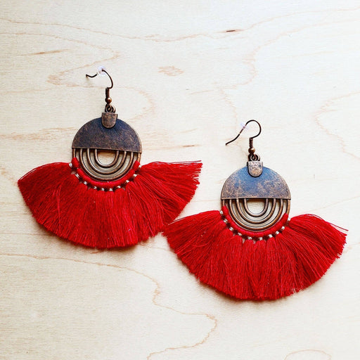 a pair of red tasseled earrings on a wooden surface