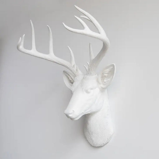 a white faux deer head mounted on a wall