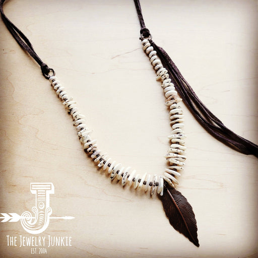 a white beaded necklace with a brown leather tassel
