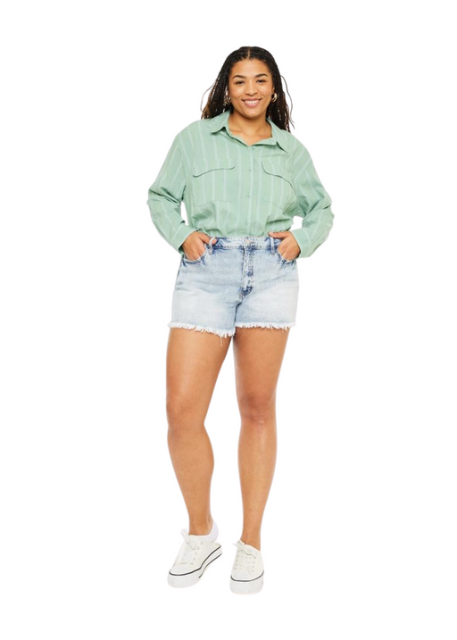 a woman in a green shirt and denim shorts