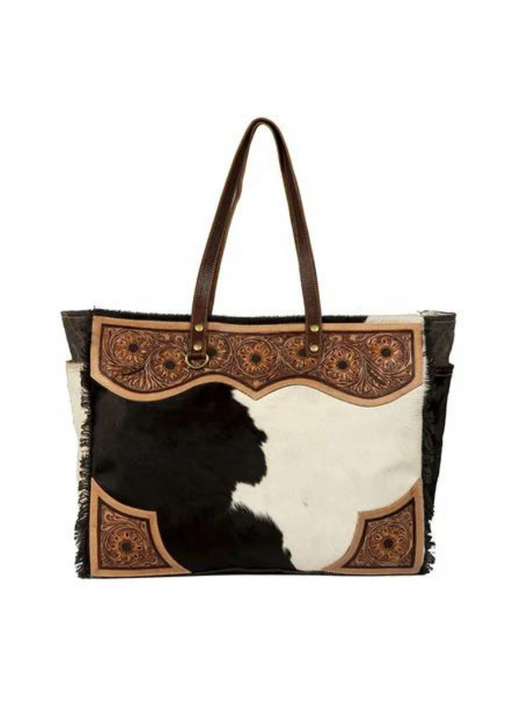 a black and white cowhide and tooled leather weekender bag
