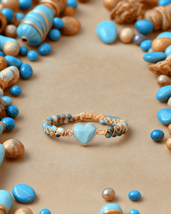 a close up of a bunch of beads on a table and a bracelet with a heart on it