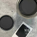 a can of black paint next to a card