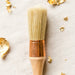 a paint brush on a white background with gold leaf