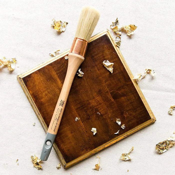 a paint brush on a white background with gold leaf