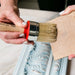 a person using a brush to paint a piece of wood