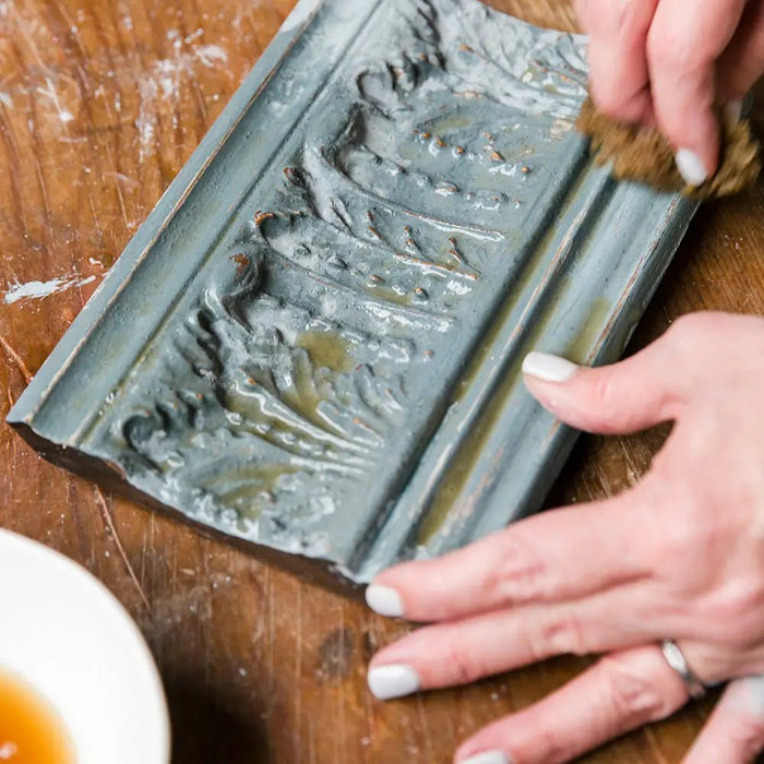 a woman is using a sponge to wipe a wood sample board