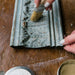 a hand brushing wax onto a sample board