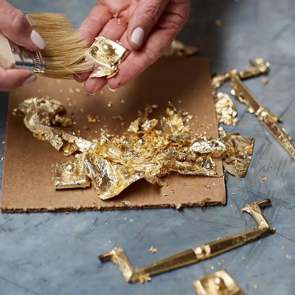 a close up of a person using a brush to paint gold