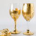 two gold colored wine glasses next to each other