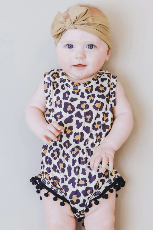 a baby wearing a leopard print romper and a headband