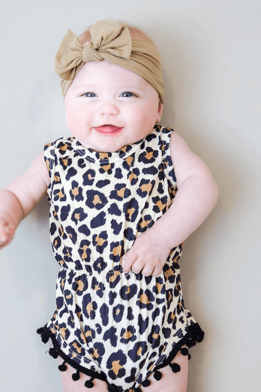 a baby girl wearing a leopard print romper and a headband