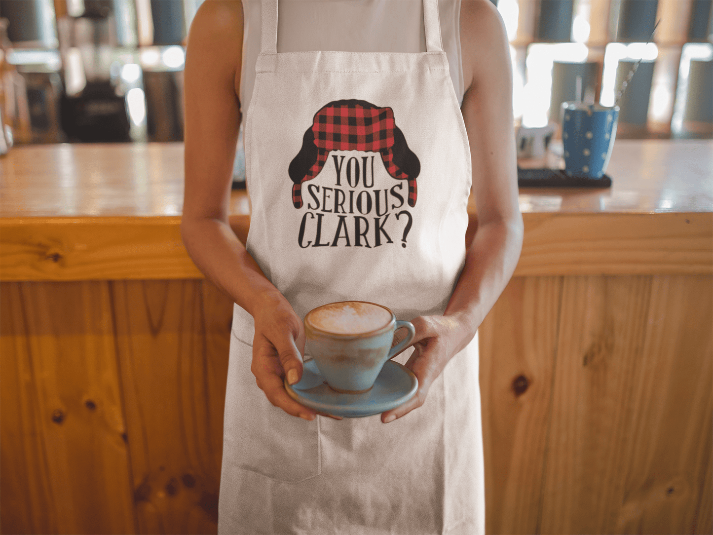 a person wearing a Christmas apron that says "you serious clark?" holding a cup of coffee