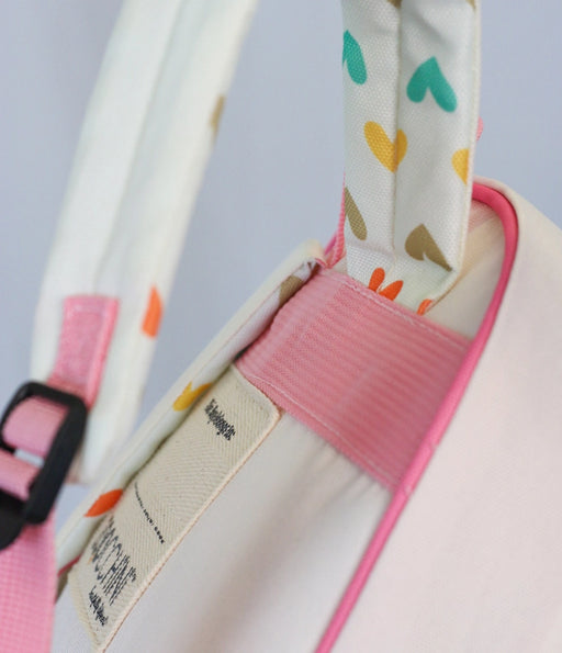 a close up of a white bag with a pink strap