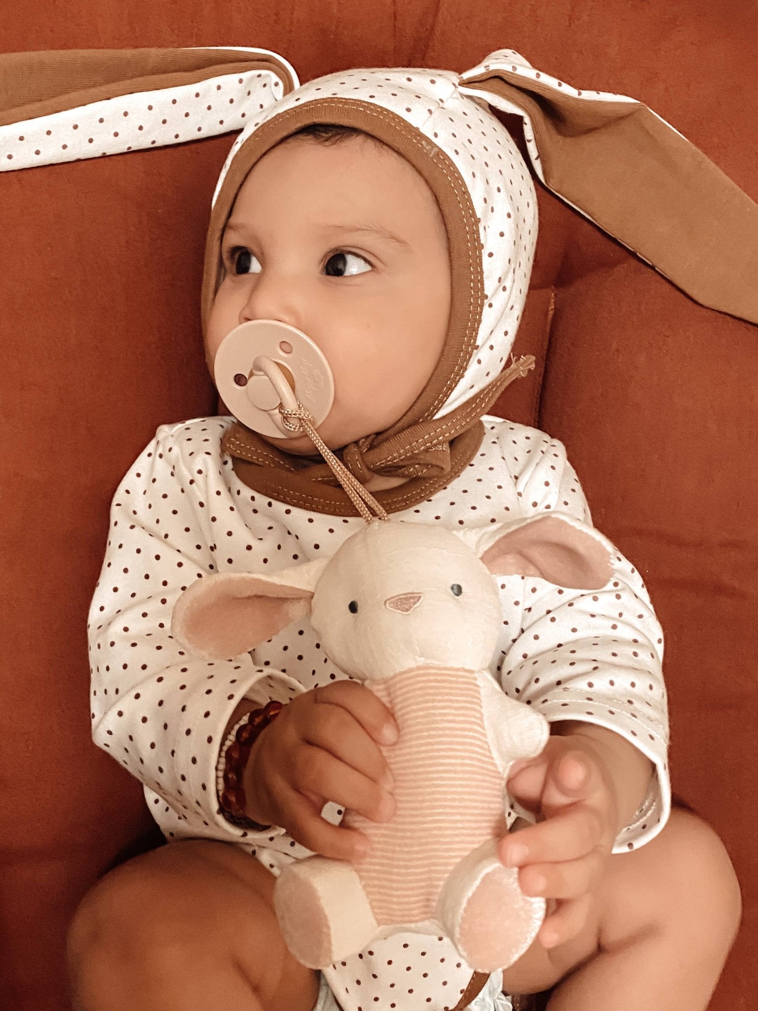 dusty pink pacifier with bunny attached in baby's mouth