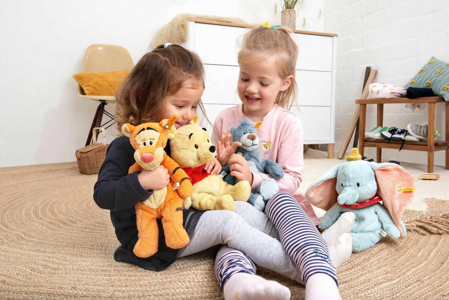 two little girls sitting on the floor with stuffed animals