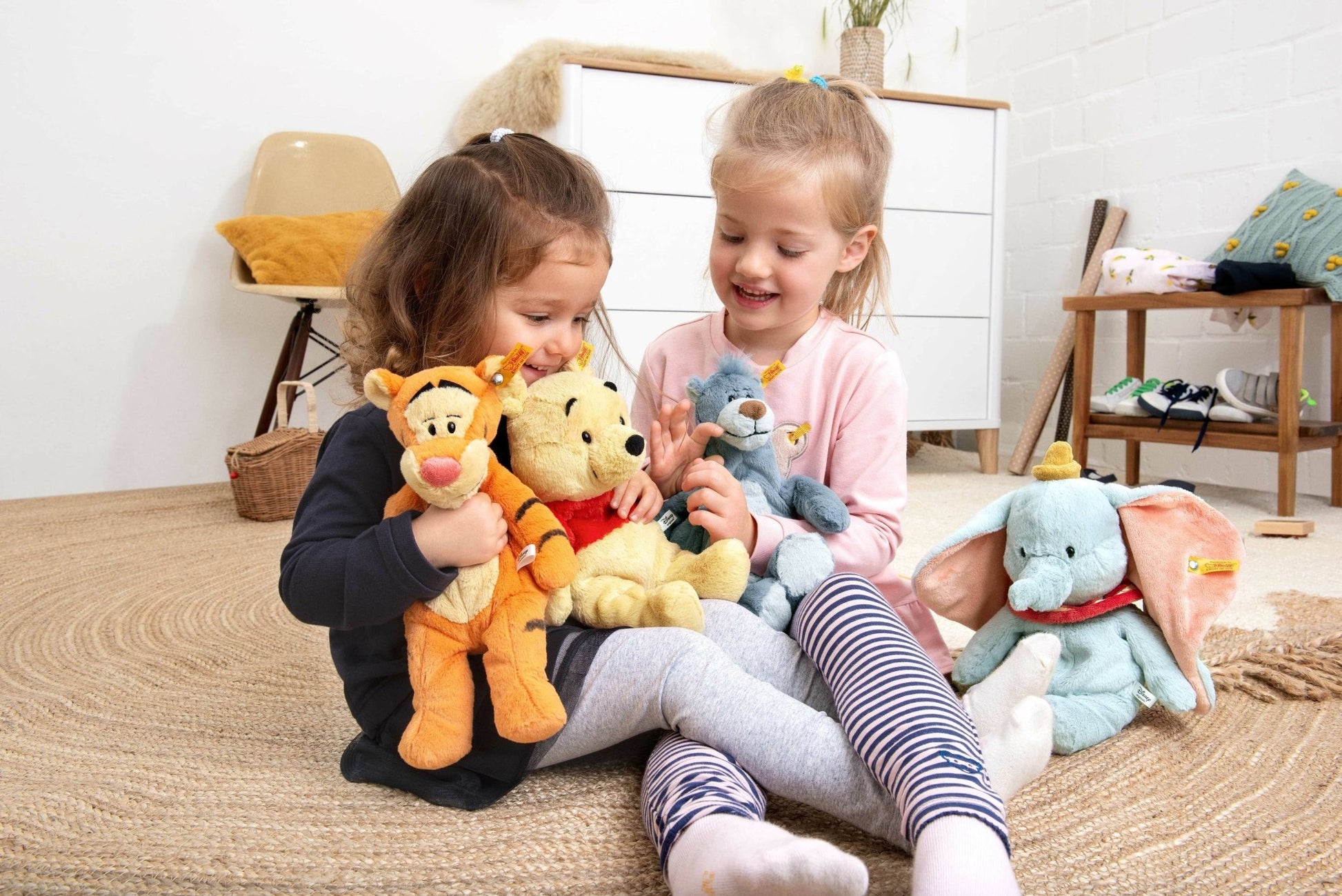 two little girls sitting on the floor with stuffed animals