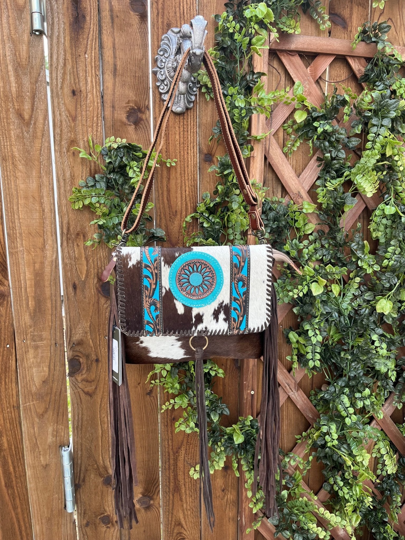 a brown and white purse hanging on a wooden fence