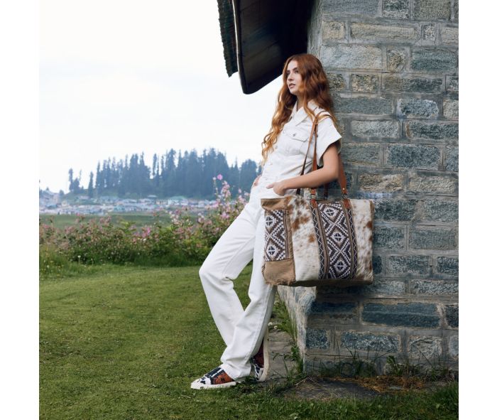 a woman leaning against a brick wall holding a bag