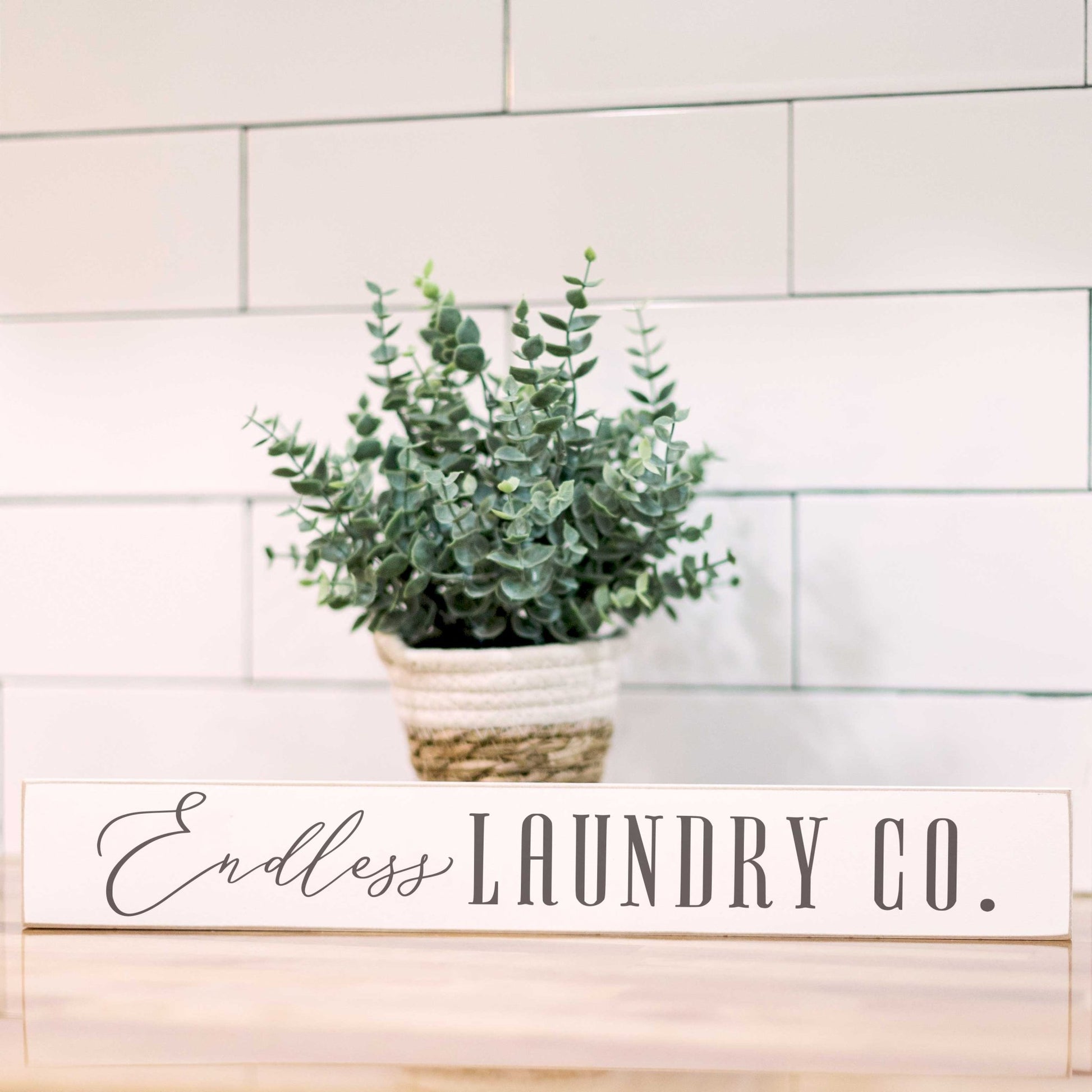 a potted plant sitting on top of a wooden table with a sign that says endless laundry co