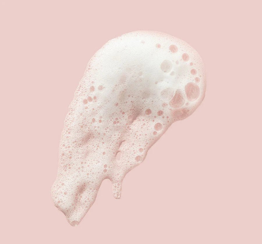 a white substance floating in the air on a pink background