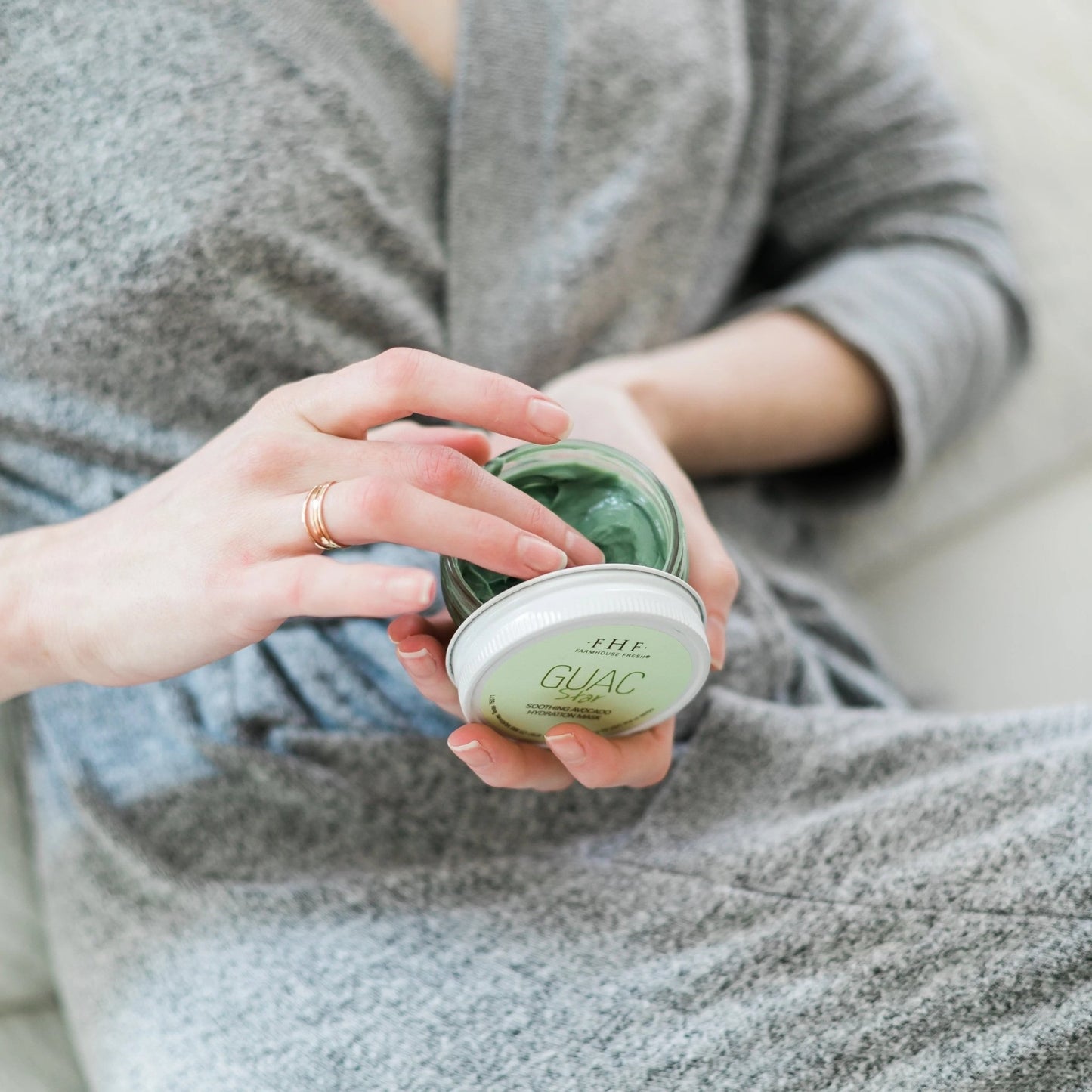 a woman sitting on a couch holding a jar of guac star