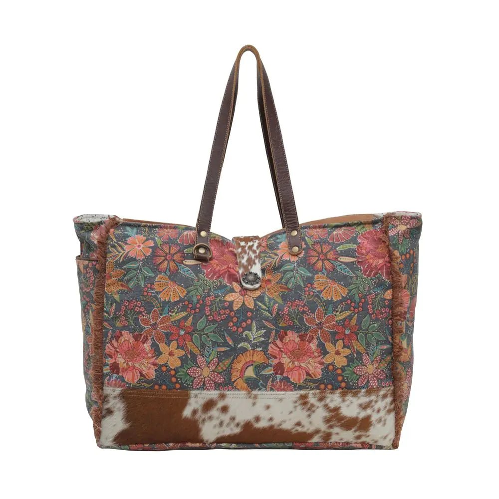 a brown and white flowered bag with a cowhide handle