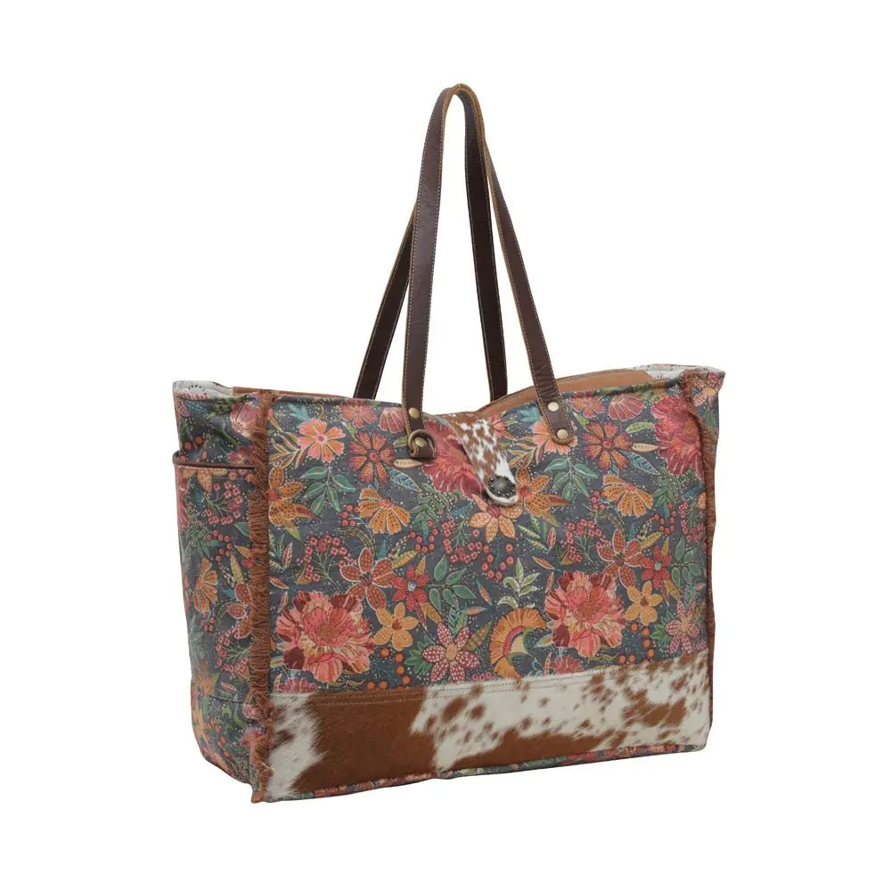 a brown and white cowhide bag with flowers on it