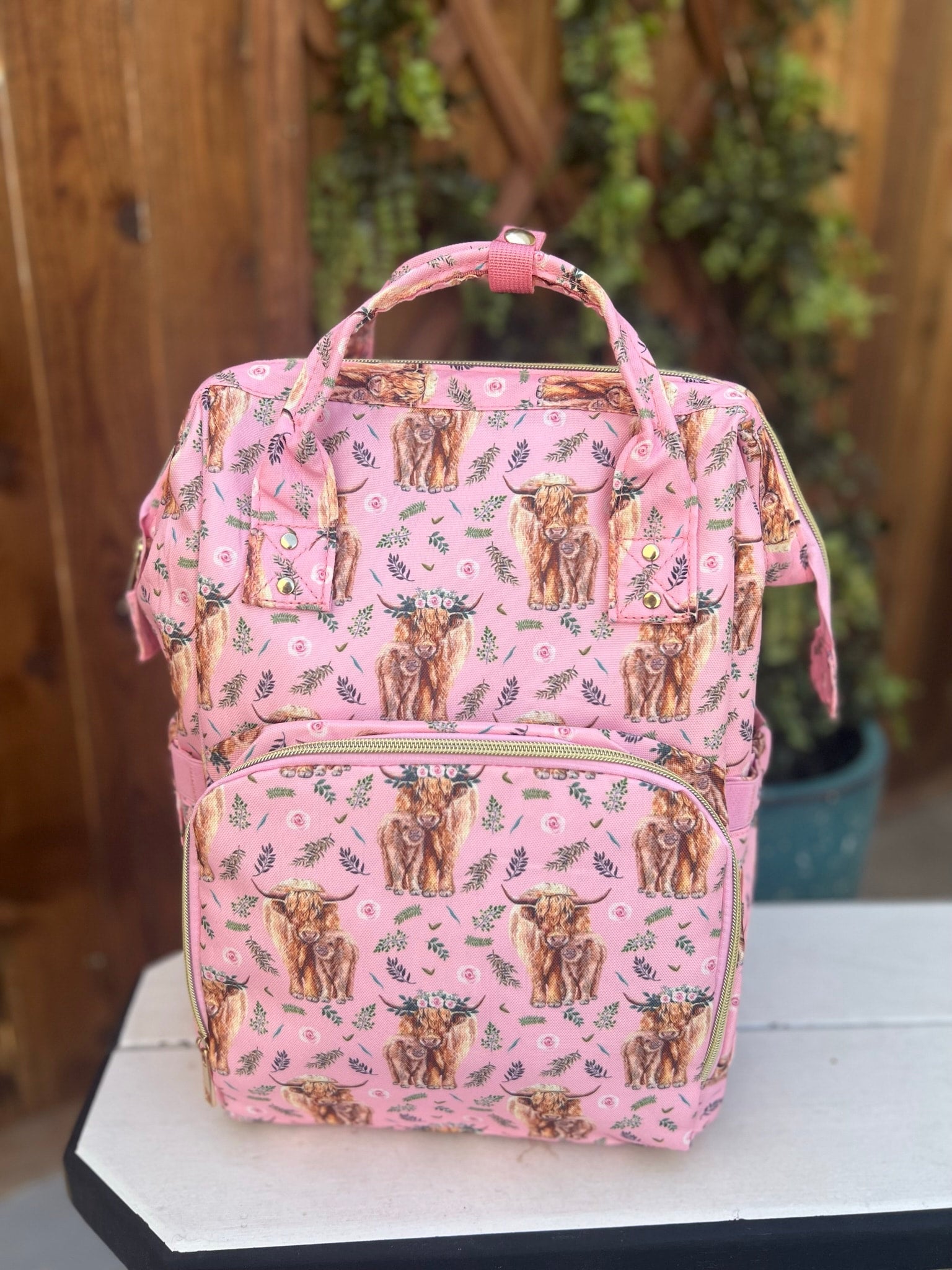 a pink diaper bag with a cow pattern on it