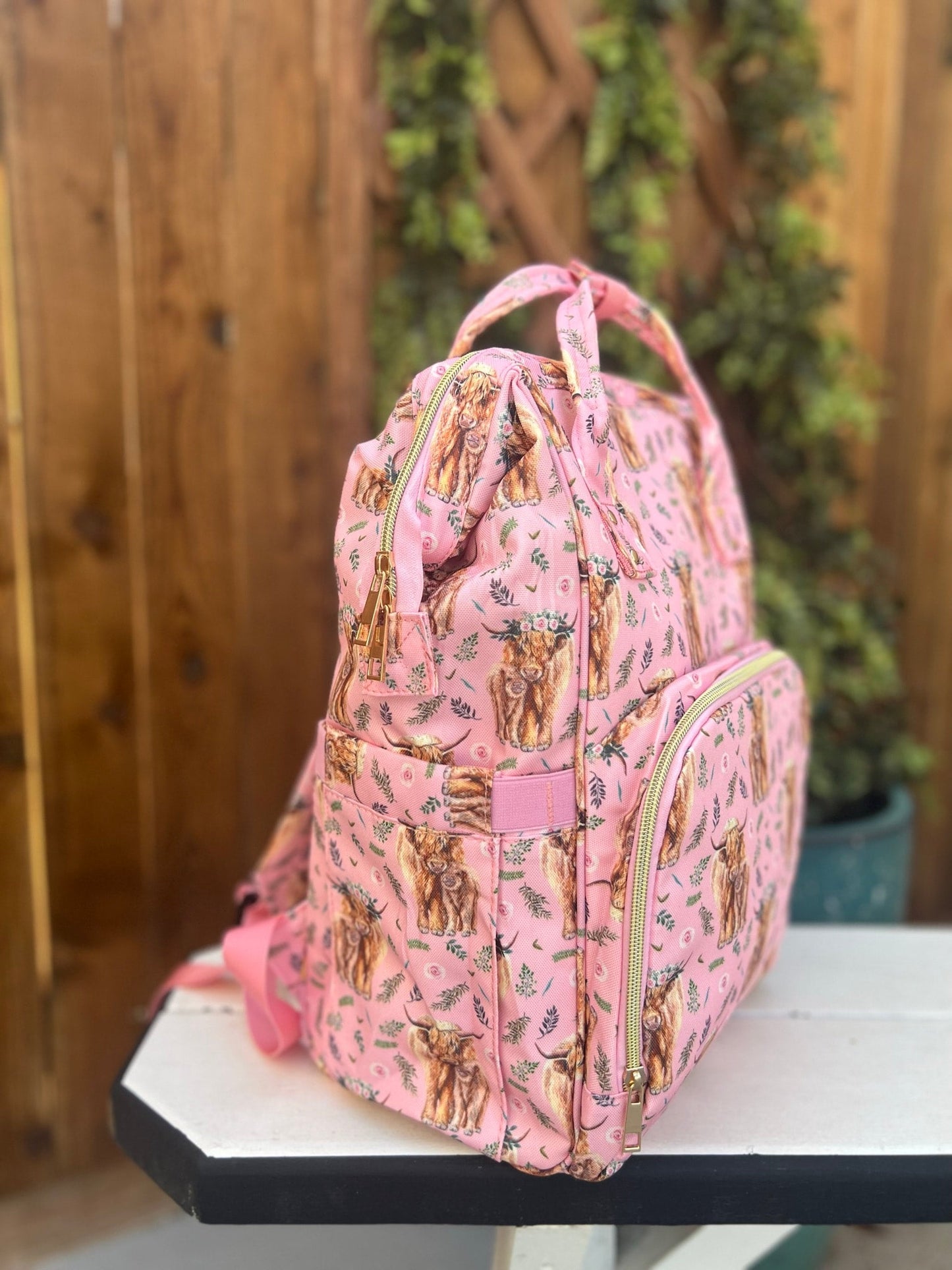 a pink diaper bag with a cow pattern on it