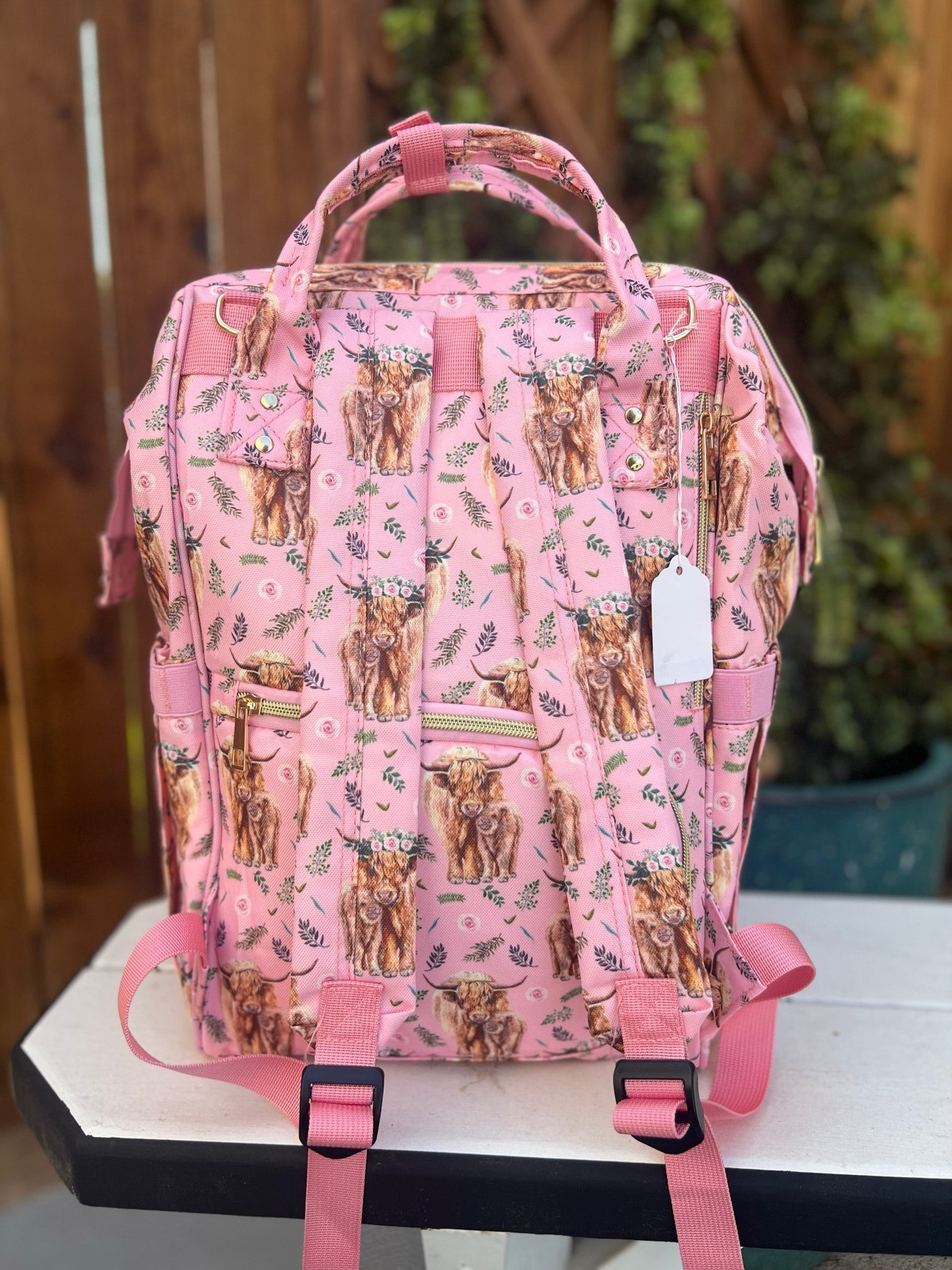 a pink diaper bag with a cow pattern on it