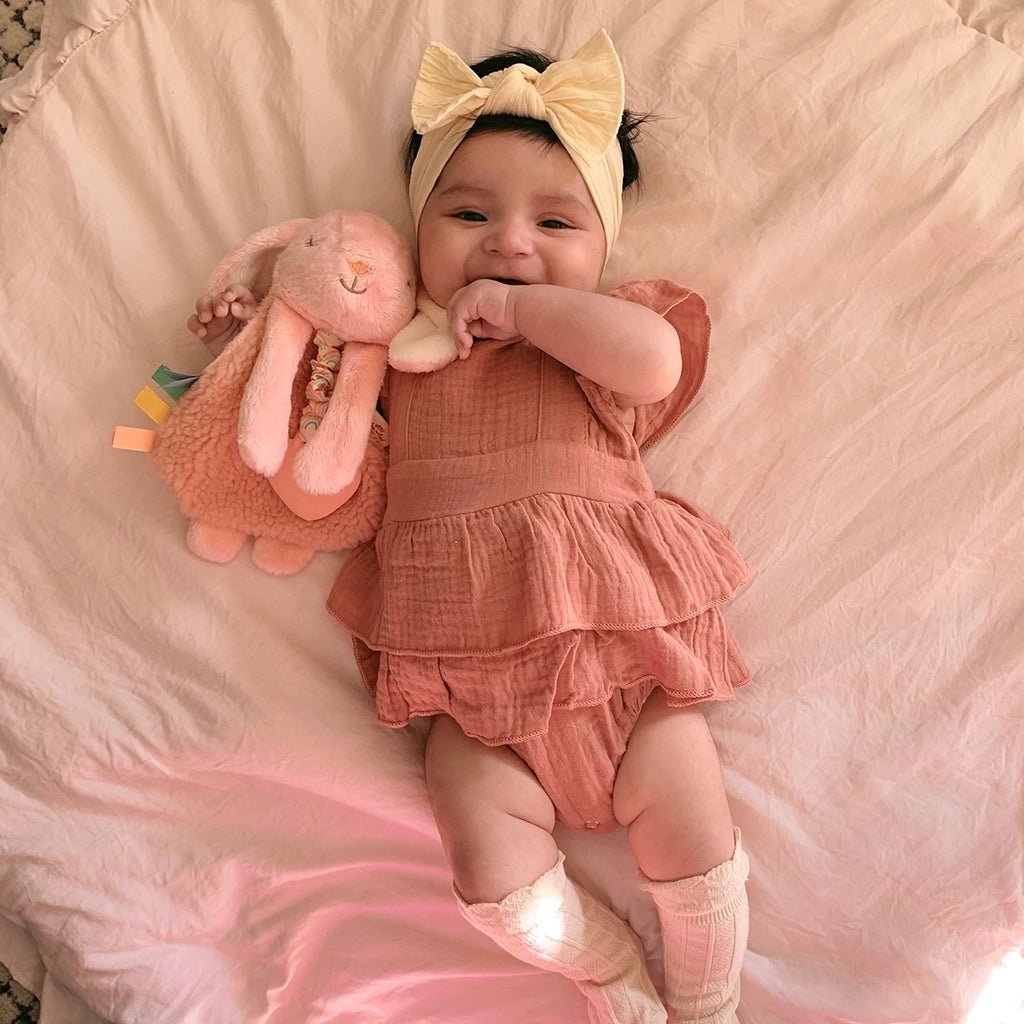 a baby laying on a bed with a stuffed animal