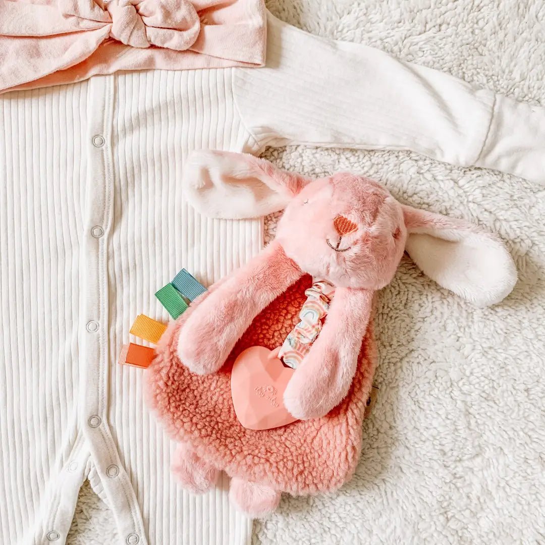 a pink bunny laying next to a pink toy