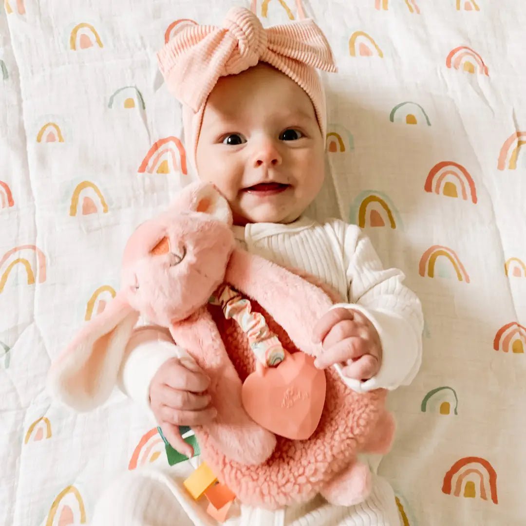 a baby is holding a pink stuffed animal